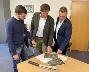 Drei Vertreter über Ausbauplan gebeugt