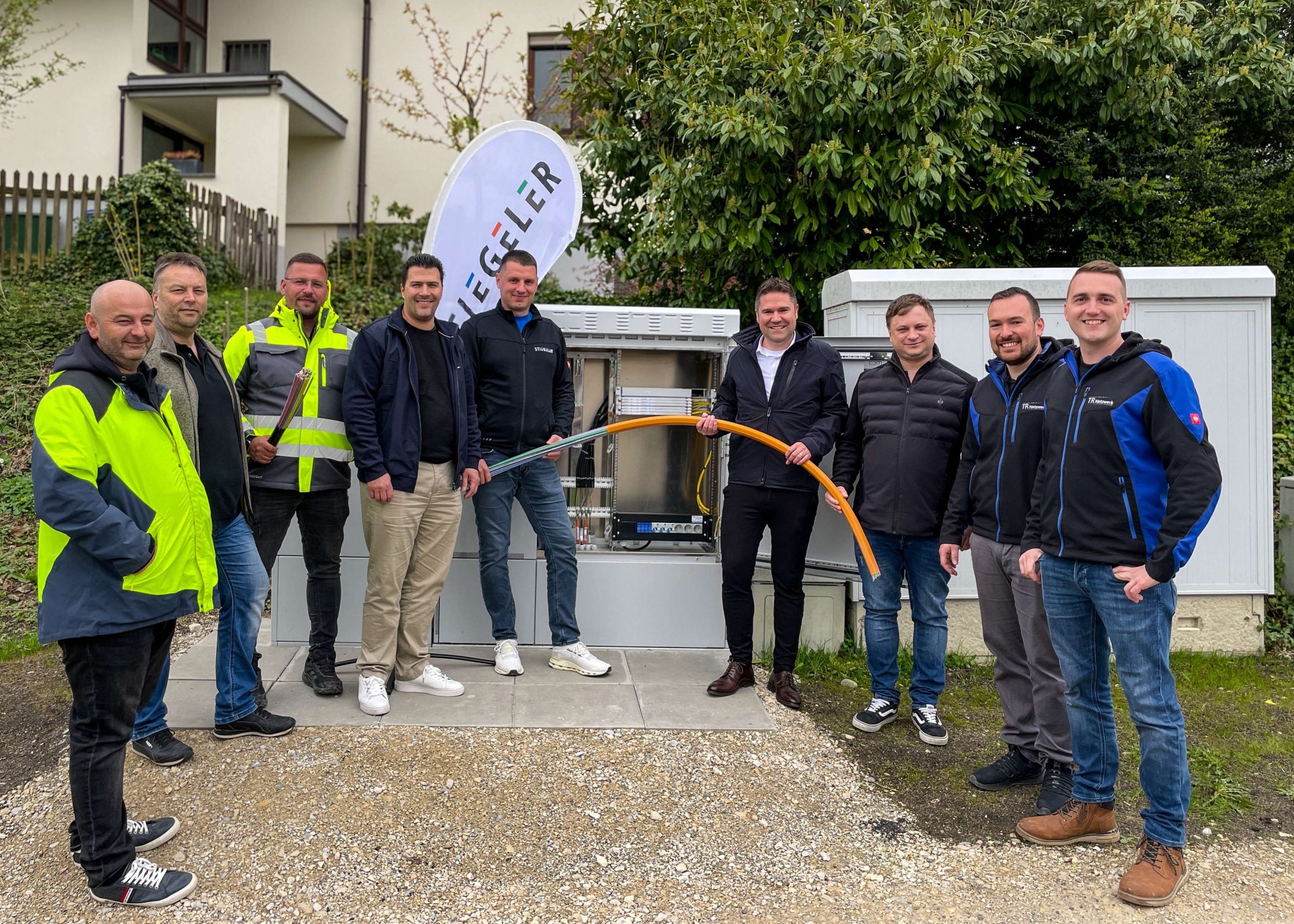 Vertreter der Gemeinde, der Baufirmen und Stiegeler-Mitarbeiter stehen vor dem Netzverteiler in Binningen für die Inbetriebnahme des Glasfasernetzes.