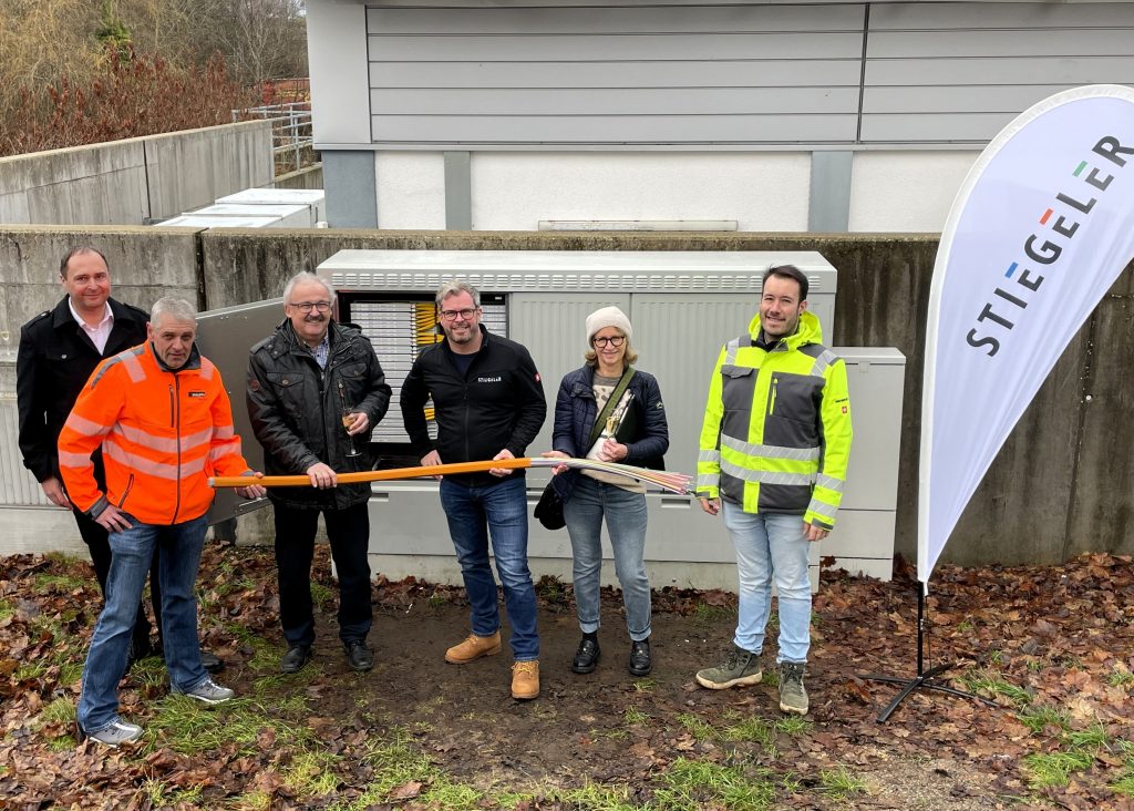Vertreter der Gemeinde, der ausführenden Tiefbaufirma und das Stiegeler-Netzbauteam vor dem Verteiler in Häusern, von dem aus die Kunden mit Glasfaser versorgt werden.