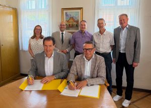 Felix Stiegeler und Lenningens Bürgermeister Michael Schlecht unterzeichnen den Zuwendungsvertrag im Beisein des Landrats, der Ortsvorsteher und Vertreter des Zweckverbands und der Gigabit Region Stuttgart.