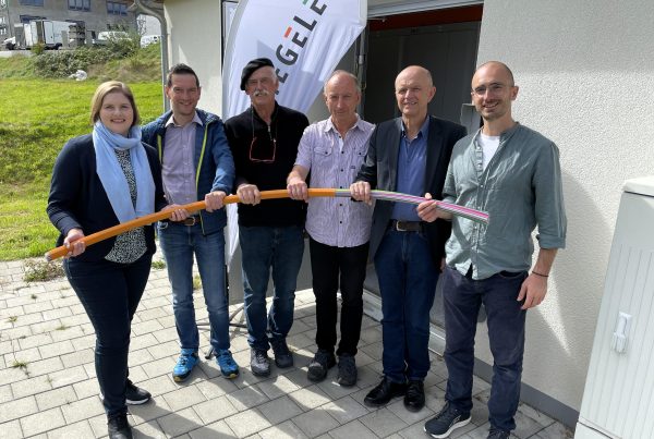 Vertreter des Netzbetreibers Stiegeler, der Planungsfirmen und der Gemeinde stehen gemeinsam mit Bürgermeister Dietmar Zäpernick vor dem neuen PoP-Gebäude für die Inbetriebnahme des Glasfasernetzes in RIckenbach.