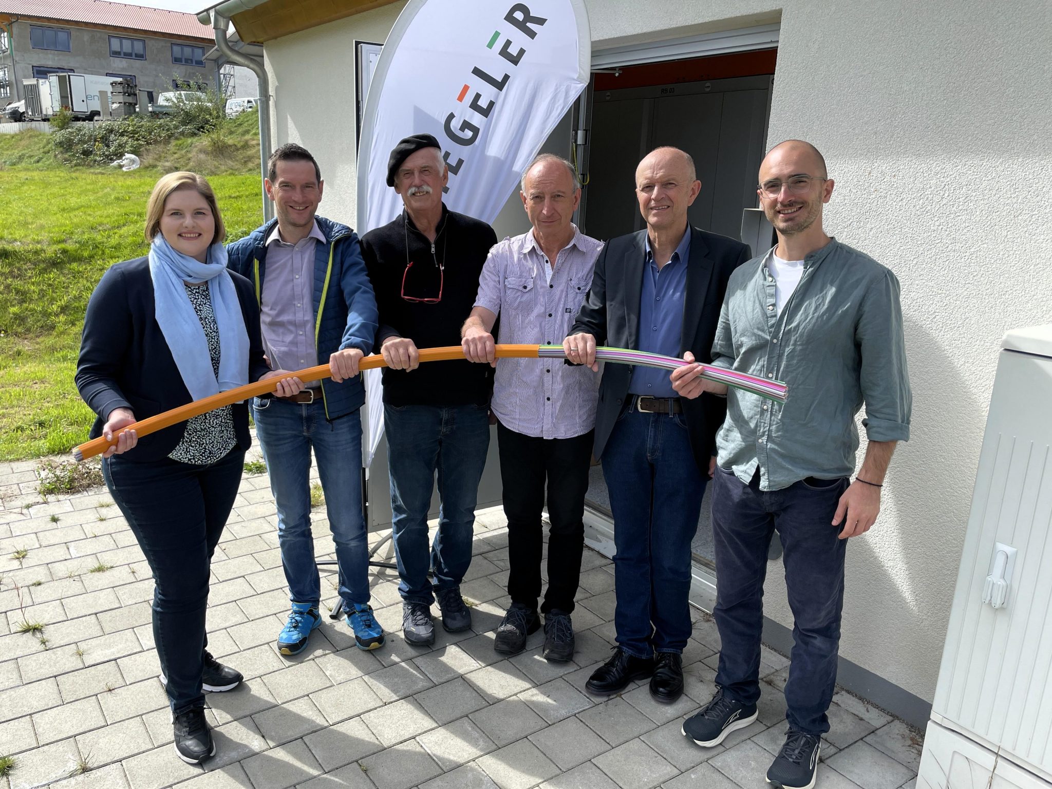 Vertreter des Netzbetreibers Stiegeler, der Planungsfirmen und der Gemeinde stehen gemeinsam mit Bürgermeister Dietmar Zäpernick vor dem neuen PoP-Gebäude für die Inbetriebnahme des Glasfasernetzes in RIckenbach.
