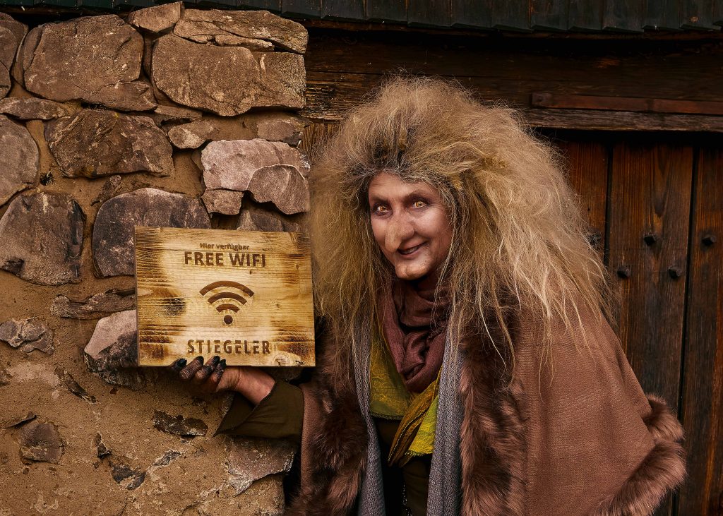 Das Bild zeigt das Key Visual der Stiegeler Markenkampagne "Keine Märchen": Eine Hexe zeigt vor einem Hexenhäuschen ein Schild mit der Aufschrift "Free Wifi".