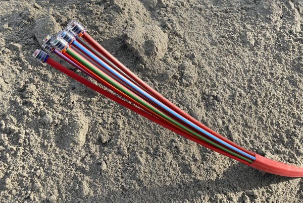 Leerrohre für den Glasfaserausbau ragen aus einem Erdhaufen.